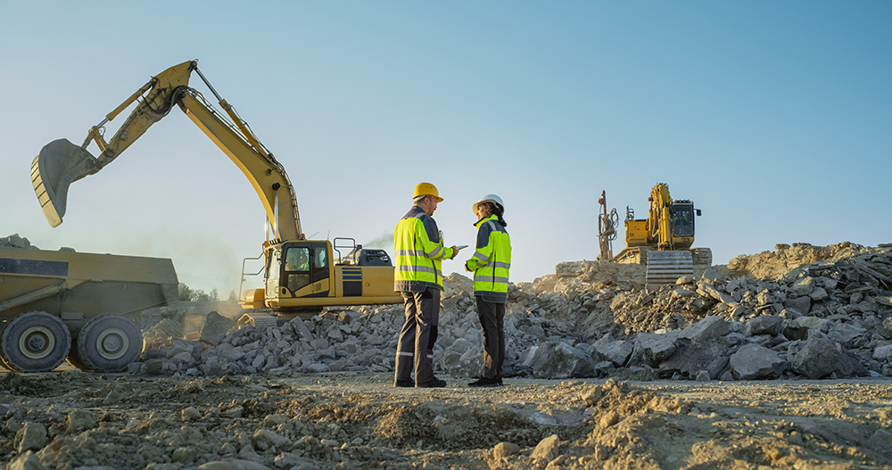Two workers on a ground-up commercial construction site.